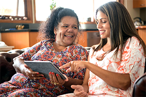 Two smiling women on sofa looking at tablet computer Two smiling women on sofa looking at tablet computer
