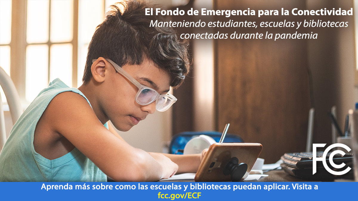 Image with Spanish text: Emergency Connectivity Fund - boy with glasses at a desk holding a pen looking at a phone