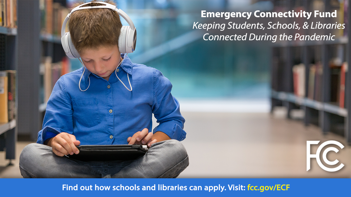 Emergency Connectivity Fund - boy with headphones sitting on library floor looking at a tablet computer
