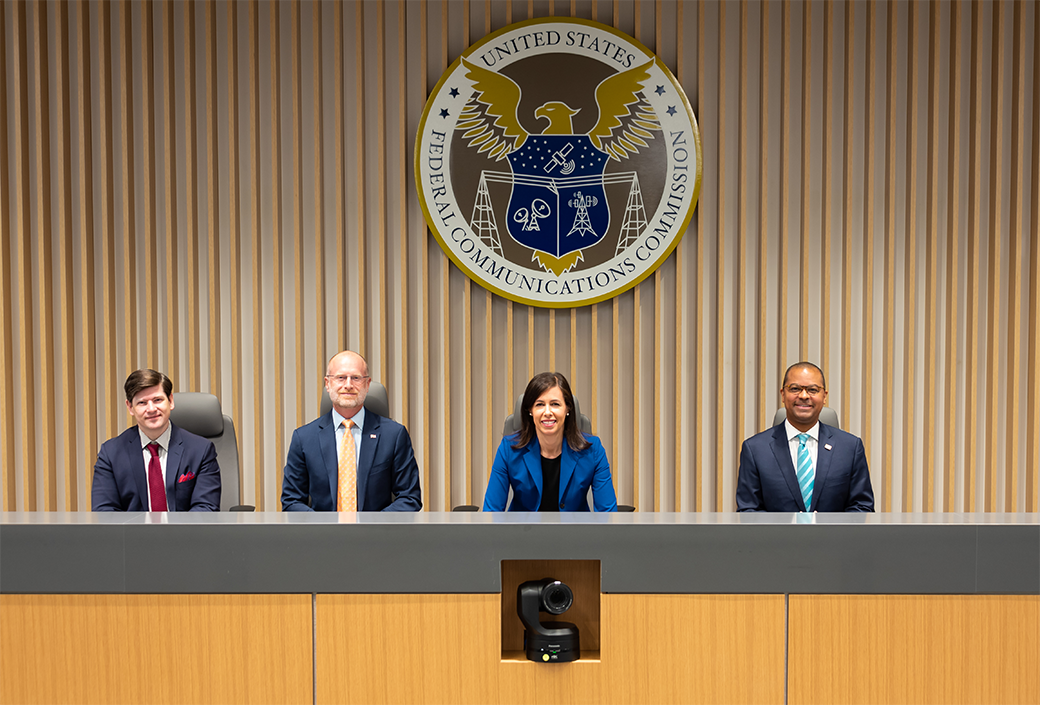 Commissioners group photo in commission meeting room at FCC's Washington DC headquarters, April 21, 2022, L to R: Commissioner Nathan Simington, Commissioner Brendan Carr, Chairwoman Jessica Rosenworcel, and Commissioner Geoffrey Starks - Click for print version.